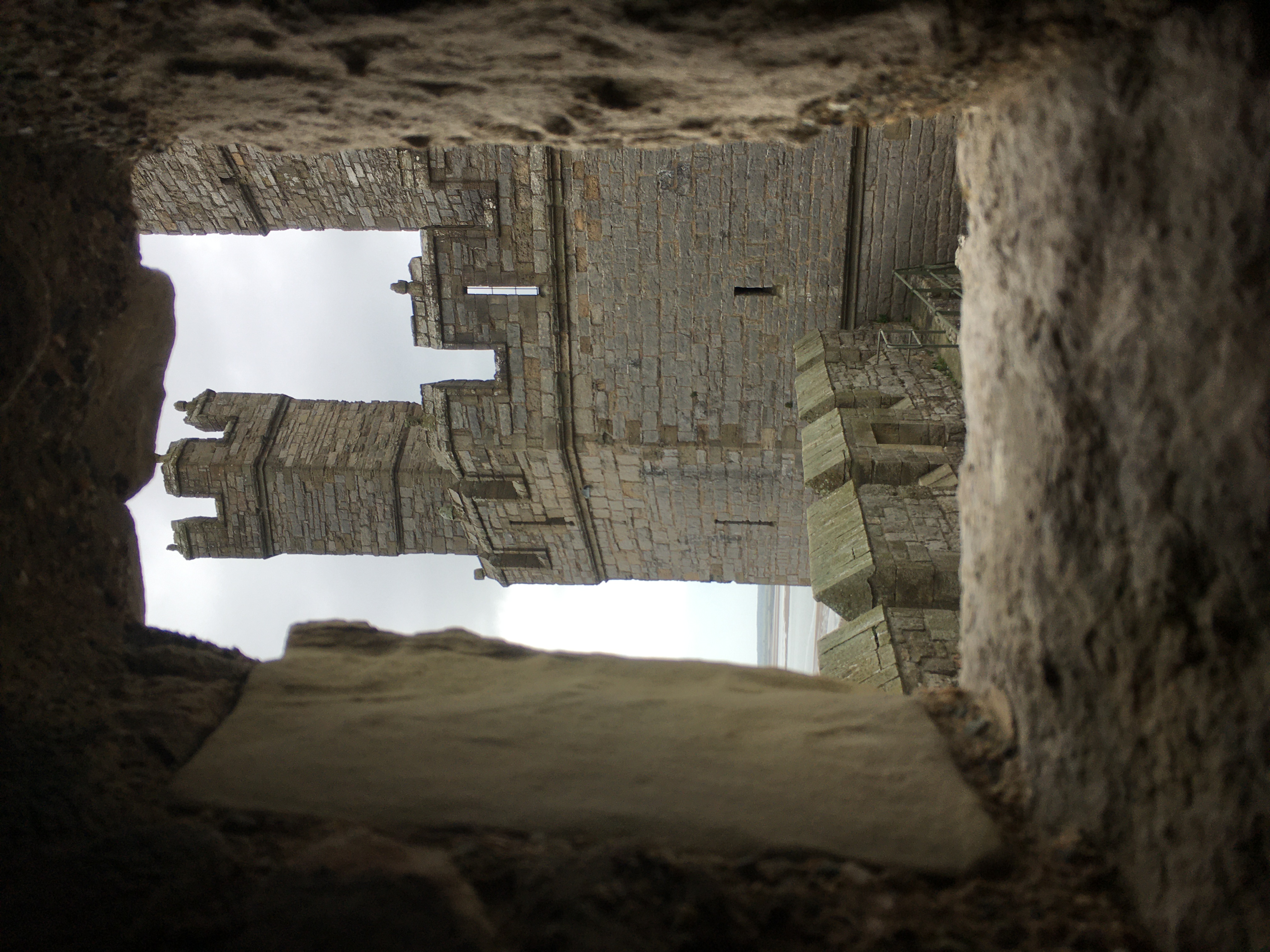 A view of a castle tower framed through the stone window of another part of the castle.