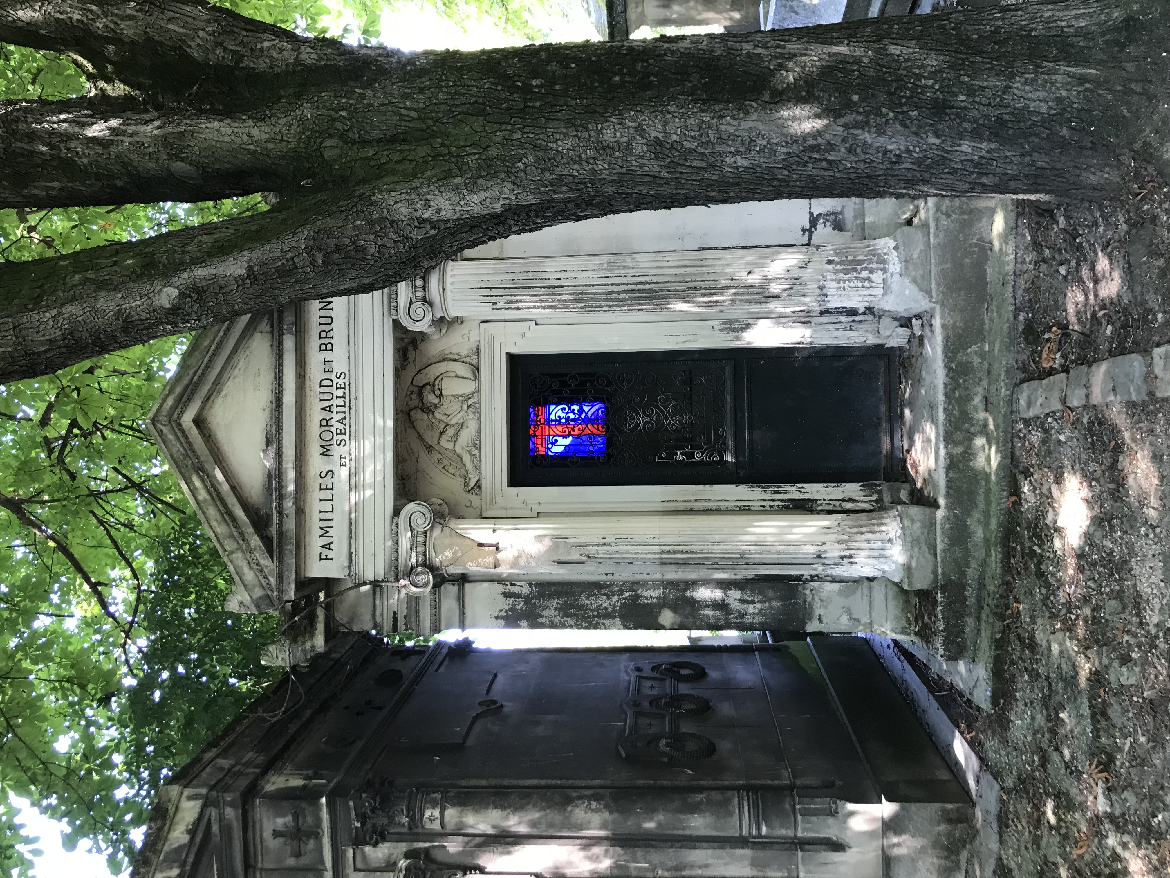 blue and red stained glass window illuminated through doorway of a mausoleum in France